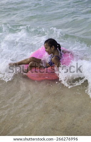little polynesian girl on her pink float ring in the ocean