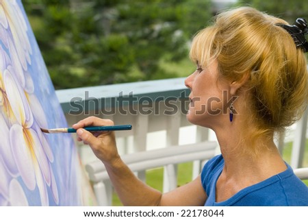 A female artist painting on canvas on her studio balcony