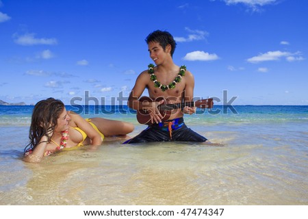 pacific island man plays his ukulele for a young woman on a hawaii beach