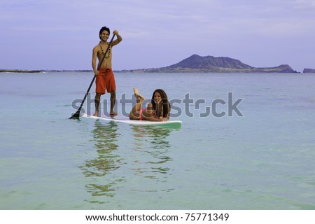 hawaiian beachboy with girl in bikini on paddle board in hawaii