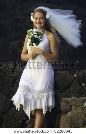 young bride with bouquet on lava rocks in hawaii