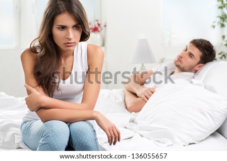 Portrait of unhappy young heterosexual couple in bedroom