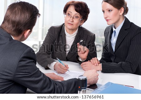 Agent (or notary public) signing documents with with senior woman and her daughter