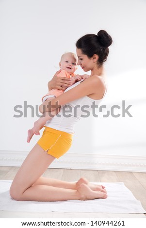 young mother does physical yoga exercises together with her baby