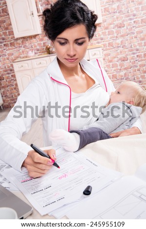 Young mother working while breastfeeding her baby