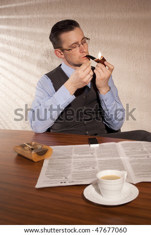 A man sitting at the table for morning coffee, smoking pipe and read the newspaper. Filtering light from a window.