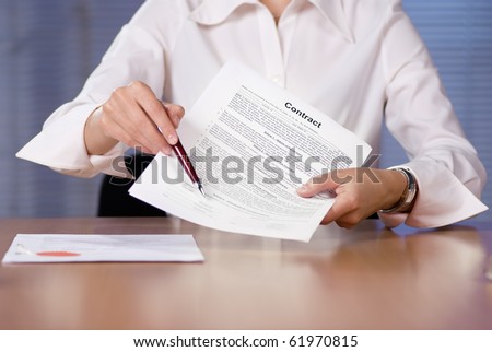 Bussinesswoman (or notary public) holding pen pointing at signature place on a contract document