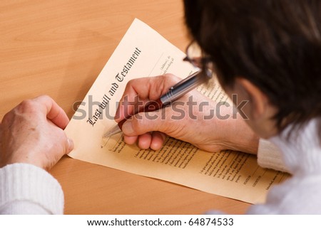 Hands of senior woman signature Last Will and Testament sitting on desk