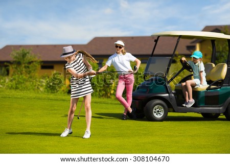 Girls playing golf at golf range at summer day