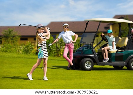 Girls playing golf at golf range at summer day