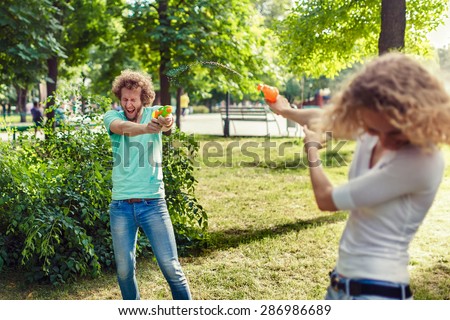 Friends playing with water pistols in the park
