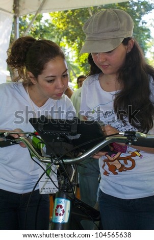 RIO DE JANEIRO - JUNE 04: Staff member and unknown girl adjusting the panel of the bicycle during the Event Green Nation Fest.  Event Green Nation Fest,June 04, 2012 in Rio de Janeiro, Brazil