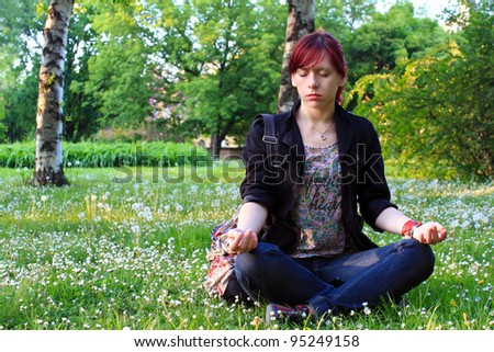 Young woman practicing yoga in a green park