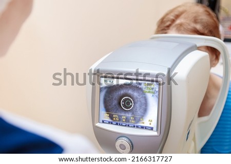 A girl optometrist examines the eyes of a patient using special modern equipment. Сток-фото © 