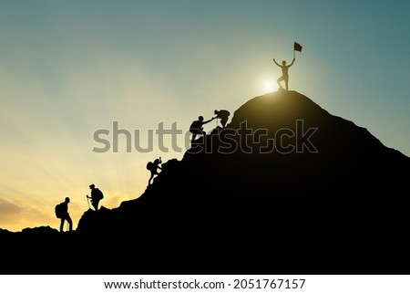Silhouette of hikers helping each other climb up a mountain. Teamwork and perseverance. Photo stock © 