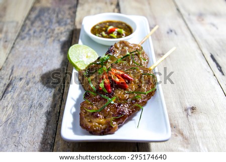 grilled pork with sweet spicy sauce  on wooden plate: Thai  food style