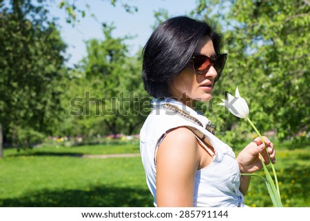 Summer mood. Woman with flowers. Portrait of a woman with white tulip in sunglasses