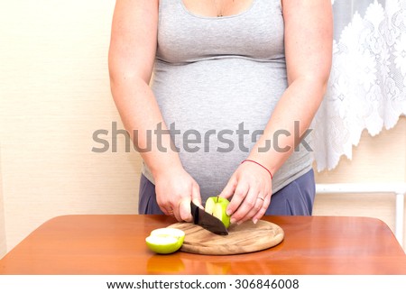 Woman and healthy food. Pregnant woman cuts green apple.
