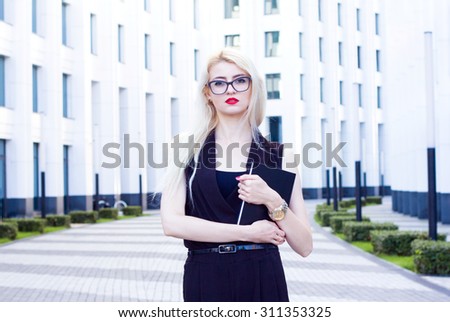 Portrait of intelligent blonde woman with a notebook on the background of the business center.