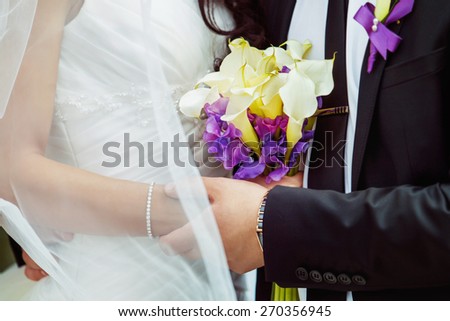Elegant man is tenderly holding by hand his beautiful bride. Love and passion at wedding day.