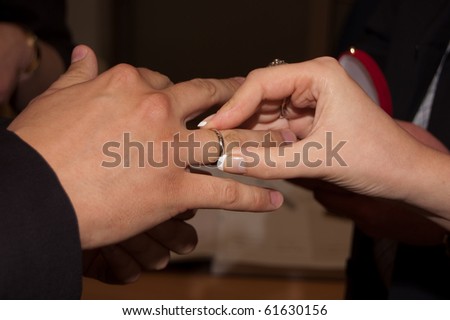 young woman putting the wedding ring on her man\'s finger