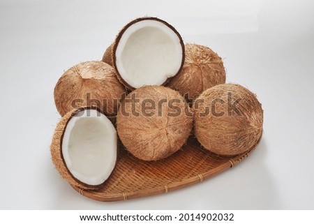 Coconut organic oil. Coconut oil in a wooden cup and coconuts fruits close-up isolated on white background.Coconut cut in half and whole coconuts in organic farm. Kelapa santan