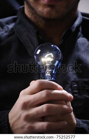 young man with light bulb in his hands and looking in camera