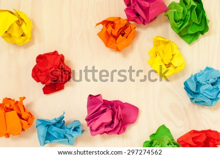 Scattered colorful crumpled paper. Colored paper balls isolated on wooden background