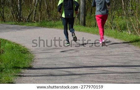 A young couple running in the forest - slightly blurred image. Happy couple exercising together. Healthy activity. Fitness sports. Outdoor jogging track in Scandinavia.
