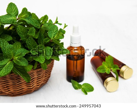Bottle of mint oil and fresh mint  on a old wooden background
