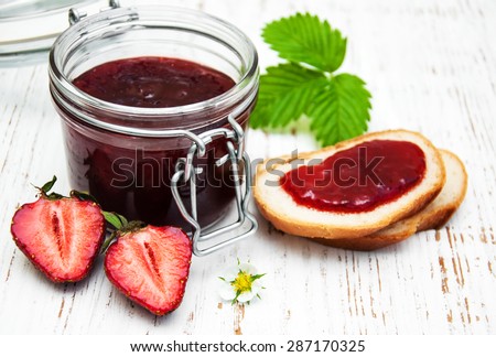 Strawberry jam and fresh strawberries on a wooden background