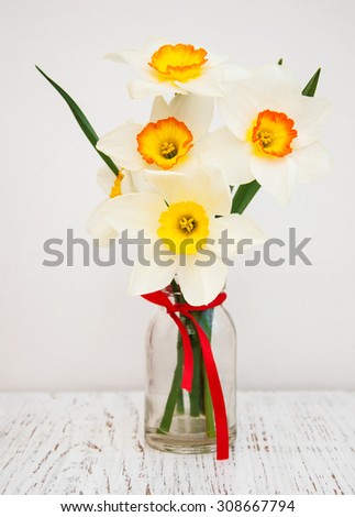 Daffodils in a vase with empty tag on a old wooden background
