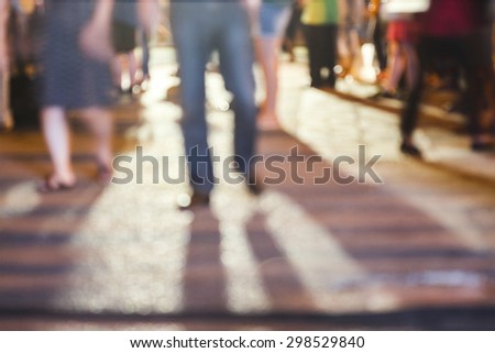 abstract blurred background of people standing on concrete ground while watching concert with shadows from the concert and a night light in the city, can use for background or your decoration.