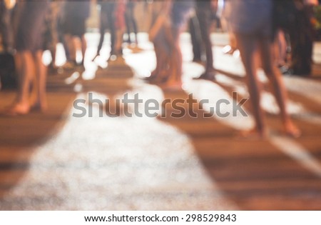 abstract blurred background of people standing on concrete ground while watching concert with shadows from the concert and a night light in the city, can use for background or your decoration.