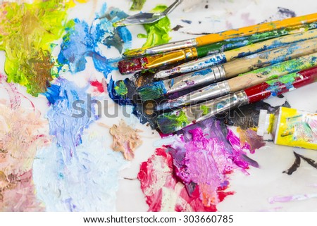Image of used paint brush  and tube of oil paint on oil paint palette of the artist