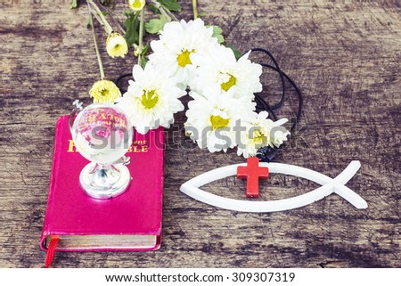 The red cross  over the white christian fish and the world globe model on the red bible with white flowers on wooden background, world mission concept.