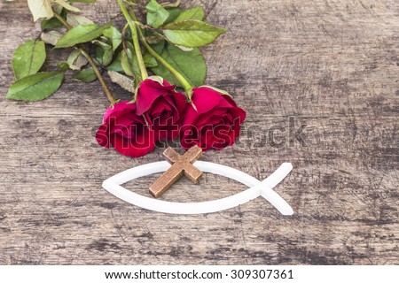 The  wooden  cross  over the white christian fish and red roses  on wooden background, world mission concept.