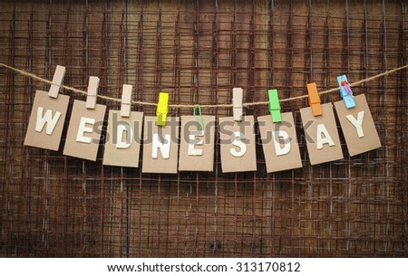 word Wednesday design by white letterpress with box paper hang on rope by wooden peg over metal net and brown wooden background, vignette effect.