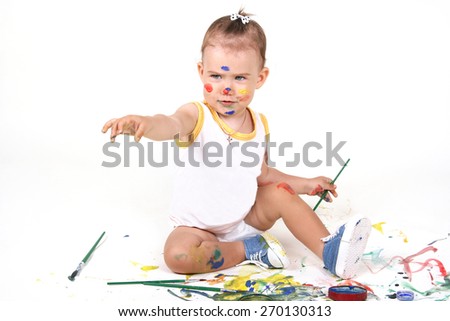 Beautiful, sweet and happy baby sitting on white background and draws paint. All smeared with colored background paint and spray