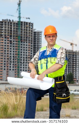Civil engineer wearing a safety vest with a plan on construction site. Belt with the tools on his belt.