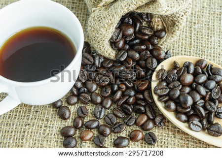 heap of fresh coffee bean from a jute bag and cup of coffee