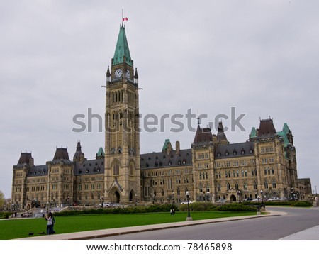 Two people talking on the lawn of Parliament Hill in Ottawa, Canadian Government, on a cloudy day.
