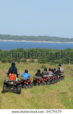 Group of young children riding quad / four-wheelers 4x4 on the meadow at the coastline