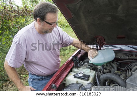 Mechanic adding windshield wiper fluid to customers vehicle