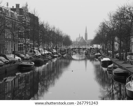 Leiden, Netherlands - 2015, March 23: Boat lined canal with church at a cloudy but calm day.