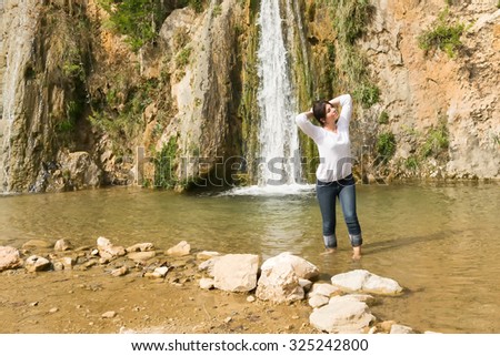 Woman model posing against a waterfall in Greece.