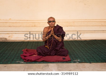 Mandalay, Myanmar - 19 February 2015 . Monk wear glasses sitting and praying in the temple.