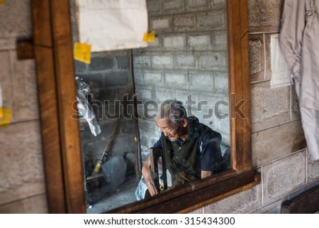 Yangon .  Myanmer 23 - February 2015 . The old man sitting in the barber shop.