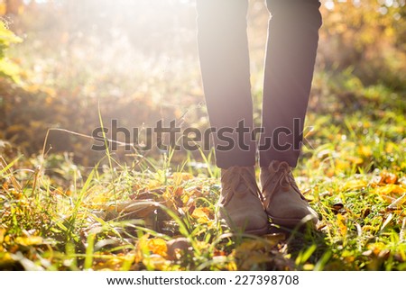 Legs in stylish boots on autumn background