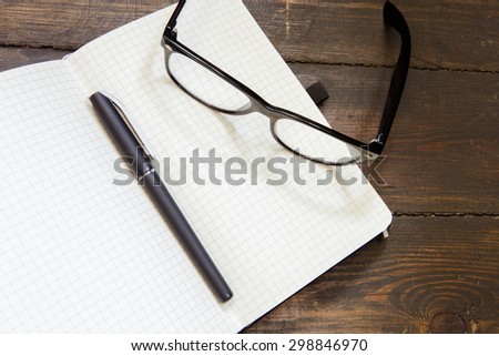 Reading glasses and notepad on wood